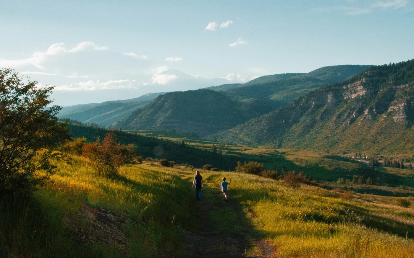 boy and man walking on mountain hill by Holly Mandarich courtesy of Unsplash.