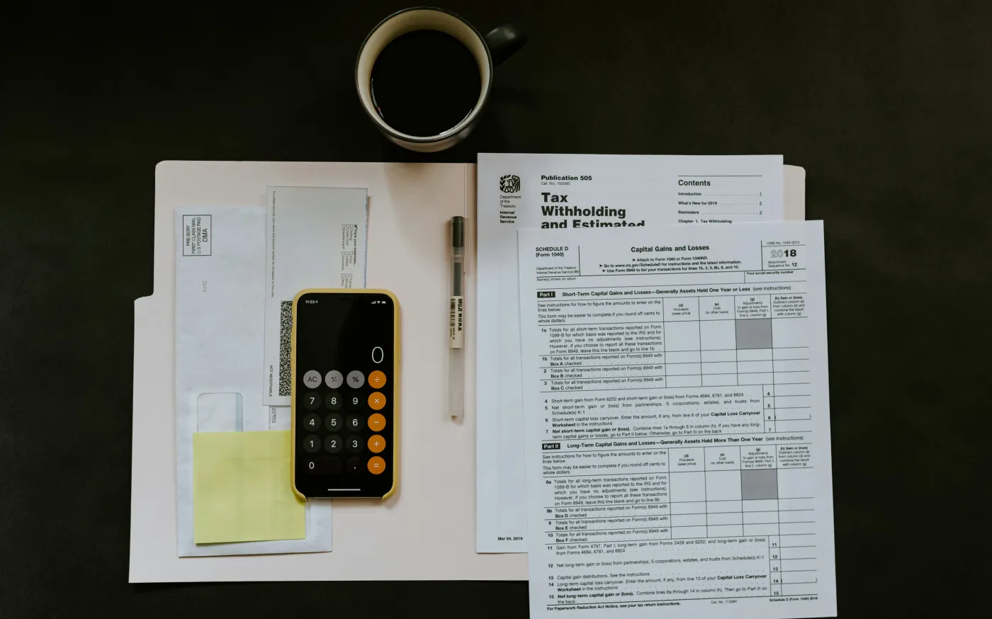 black Android smartphone near ballpoint pen, tax withholding certificate on top of white folder by Kelly Sikkema courtesy of Unsplash.