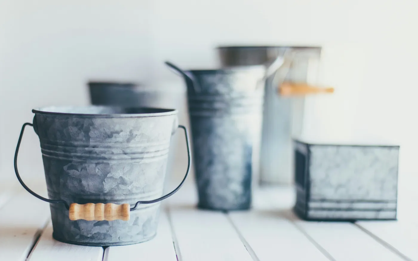 gray steel bucket on brown wooden bucket by Sixteen Miles Out courtesy of Unsplash.