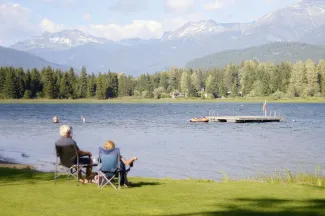 two persons sitting on grass facing the lake by Max Harlynking courtesy of Unsplash.