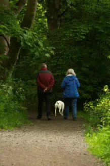 man and woman with white dog walking on dirt road during daytime by Diana Parkhouse courtesy of Unsplash.
