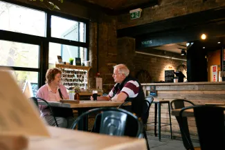 Elderly couple talking at a cafe table by Centre for Ageing Better courtesy of Unsplash.