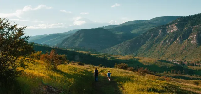 boy and man walking on mountain hill by Holly Mandarich courtesy of Unsplash.