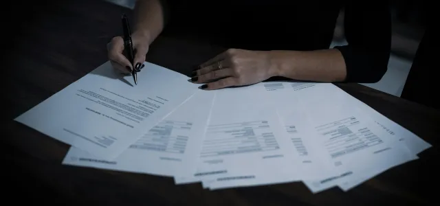 a woman sitting at a table with lots of papers by Dimitri Karastelev courtesy of Unsplash.
