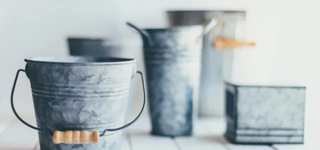 gray steel bucket on brown wooden bucket by Sixteen Miles Out courtesy of Unsplash.